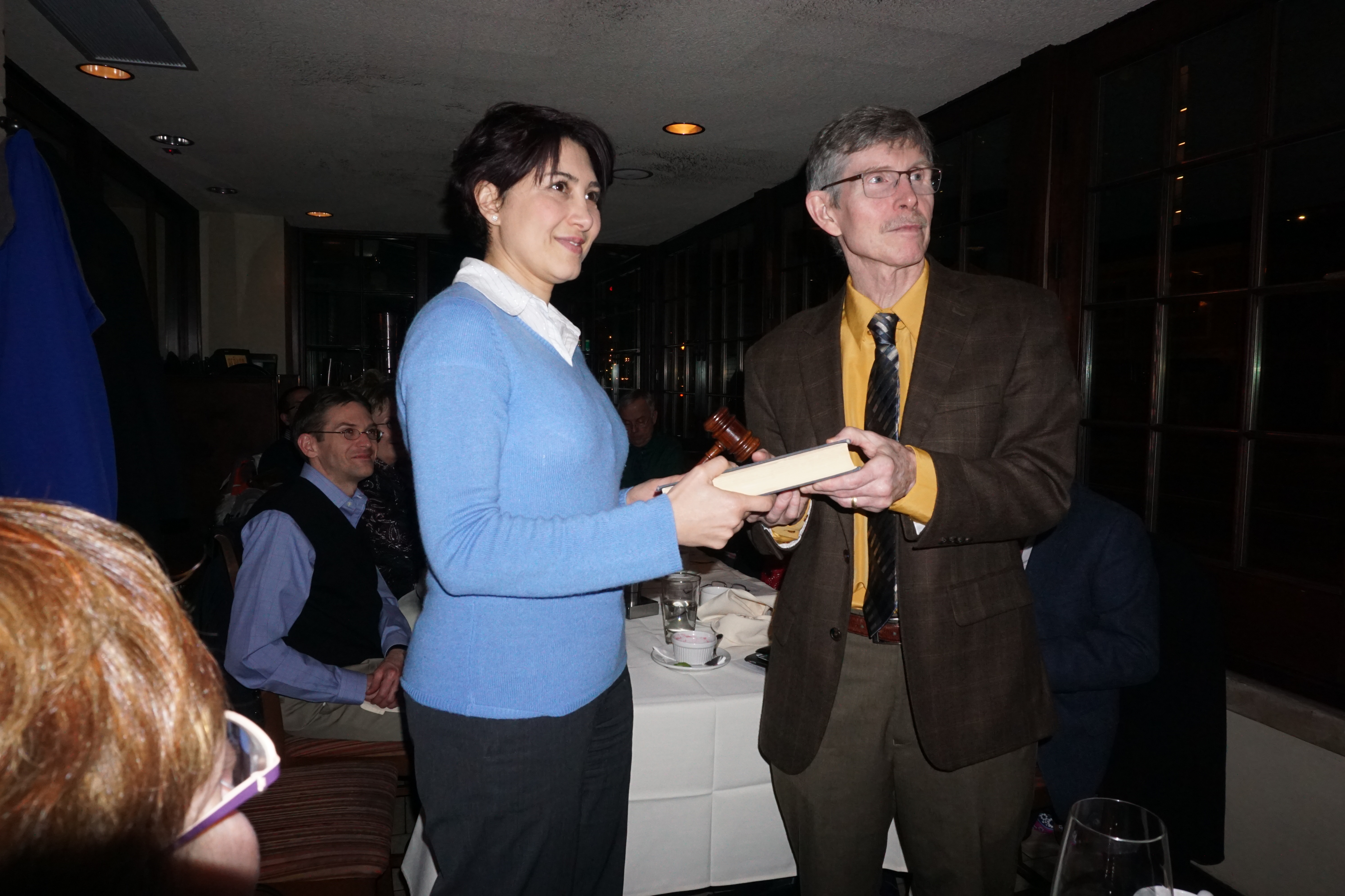 The book-and-gavel pass signifies the start of a new Section year (Pegah, left; Jim, right).