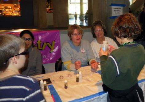 Pegah Jalili, Ann Feil, and Sheryl Loux explain about Enzymes Aid Digestion & Cleaning at the St. Louis Science Center for National Chemistry Week on 8/26/13.